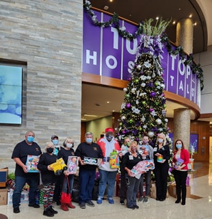 Group standing in Silver Cross lobby with a donation of toys